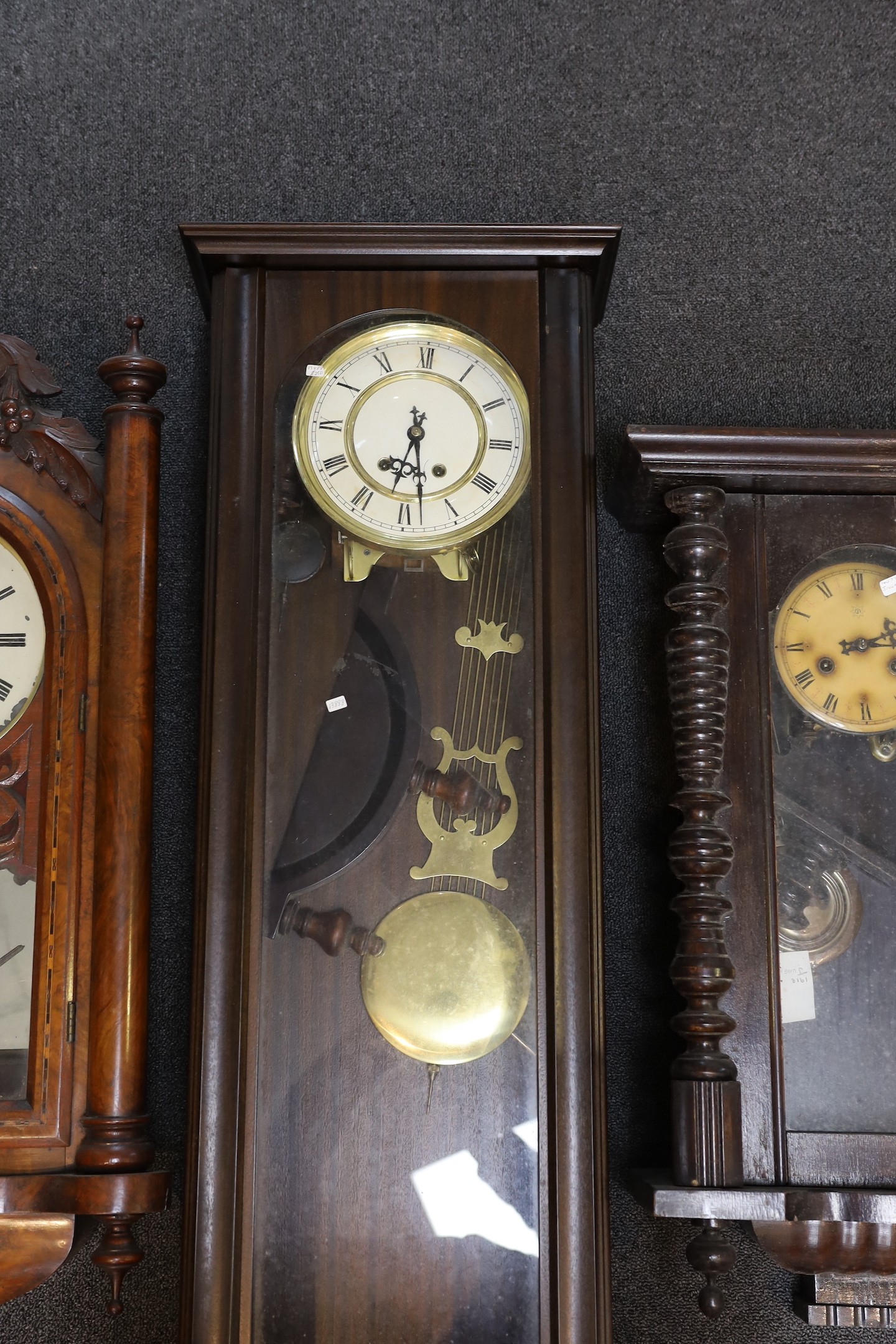 A late 19th century American carved inlaid walnut drop dial wall clock, height 94 cms together with two later Vienna type wall clocks.